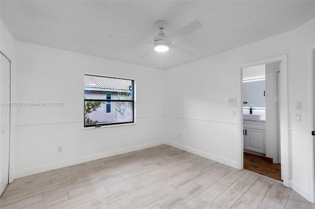 unfurnished room with a sink, baseboards, light wood finished floors, and ceiling fan