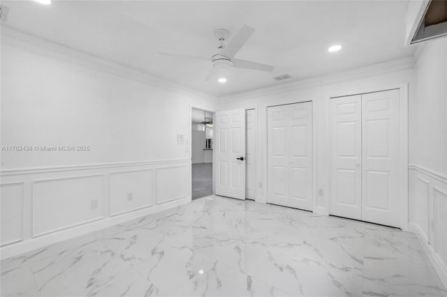 unfurnished bedroom with recessed lighting, multiple closets, ornamental molding, and a decorative wall