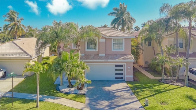 mediterranean / spanish-style house with driveway, stucco siding, a front lawn, a garage, and a tile roof