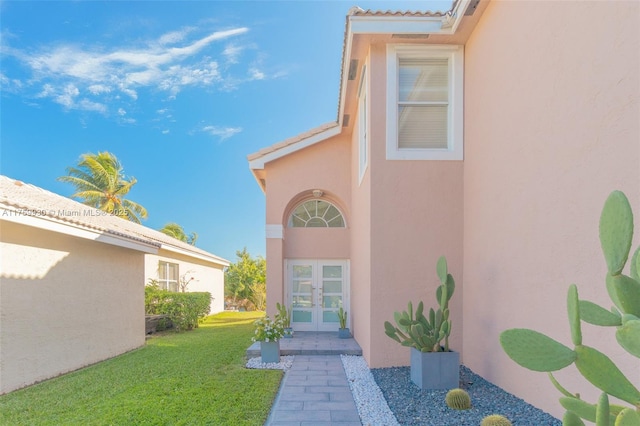 doorway to property with french doors, a lawn, a tile roof, and stucco siding