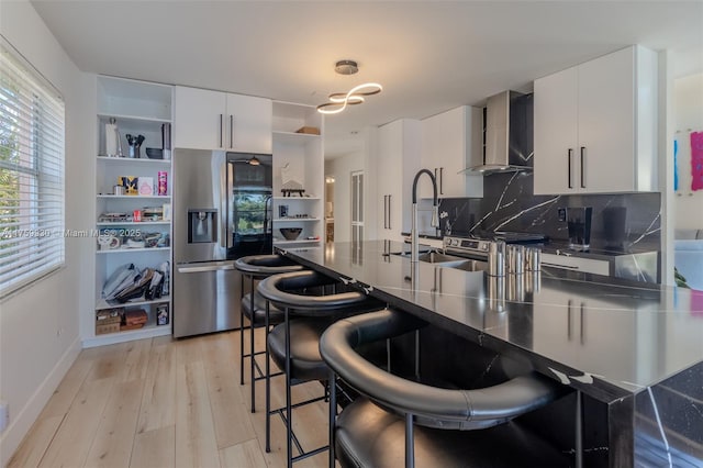 kitchen featuring open shelves, appliances with stainless steel finishes, dark countertops, wall chimney exhaust hood, and modern cabinets