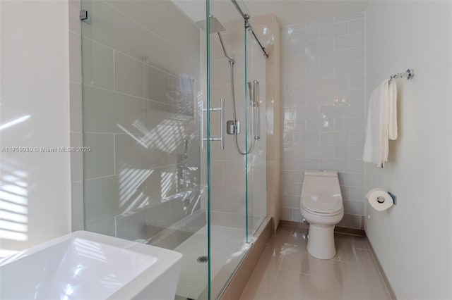 bathroom with a sink, toilet, a stall shower, and tile patterned flooring