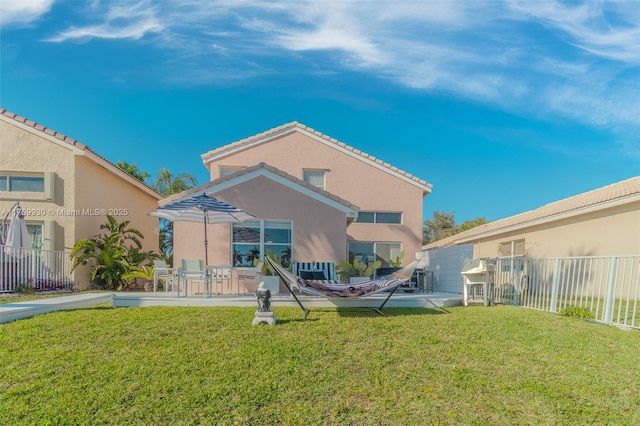 rear view of house with a patio area, a yard, fence, and stucco siding