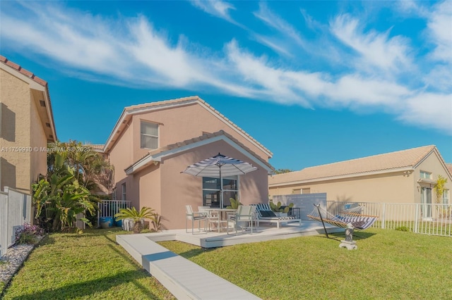 rear view of house featuring stucco siding, a lawn, a patio, and fence