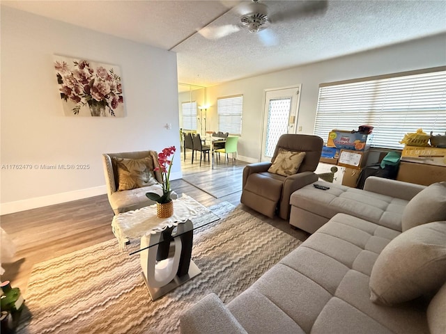 living room with a ceiling fan, wood finished floors, baseboards, and a textured ceiling