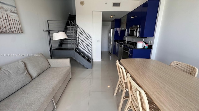 living room with light tile patterned floors, visible vents, and stairs