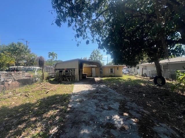 view of front of home featuring a detached carport, driveway, and fence