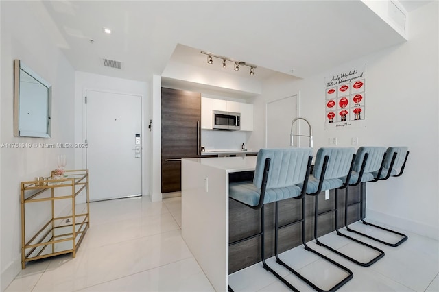 kitchen with visible vents, a breakfast bar, light countertops, a peninsula, and stainless steel appliances