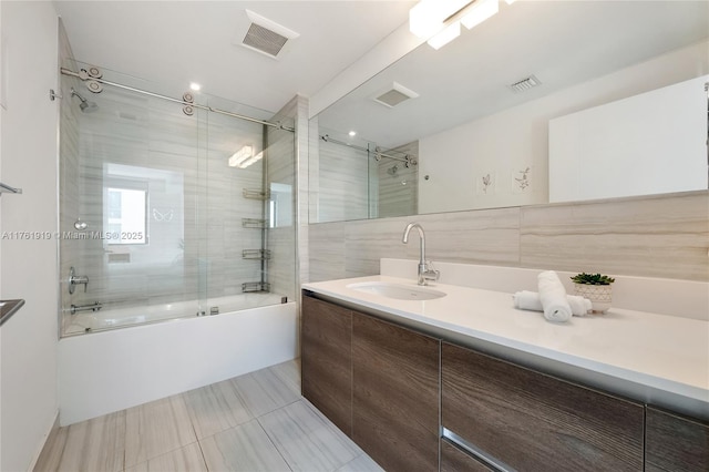 bathroom with visible vents, enclosed tub / shower combo, tile walls, and vanity