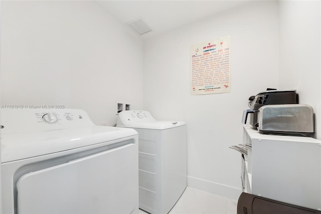 clothes washing area with laundry area, washing machine and dryer, baseboards, and visible vents