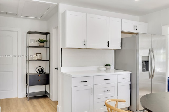 kitchen with white cabinetry, light countertops, stainless steel fridge with ice dispenser, and light wood-style floors