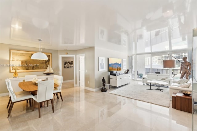 living area featuring a tray ceiling, baseboards, and a towering ceiling