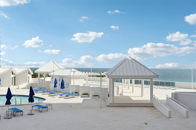 view of patio / terrace featuring a gazebo, a community pool, a water view, and fence