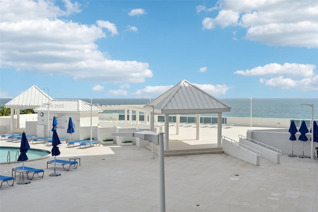 view of patio / terrace featuring a gazebo, fence, a community pool, and a water view