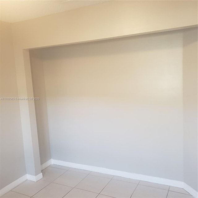 empty room featuring light tile patterned floors and baseboards