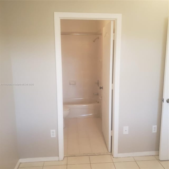 hallway featuring baseboards and light tile patterned flooring