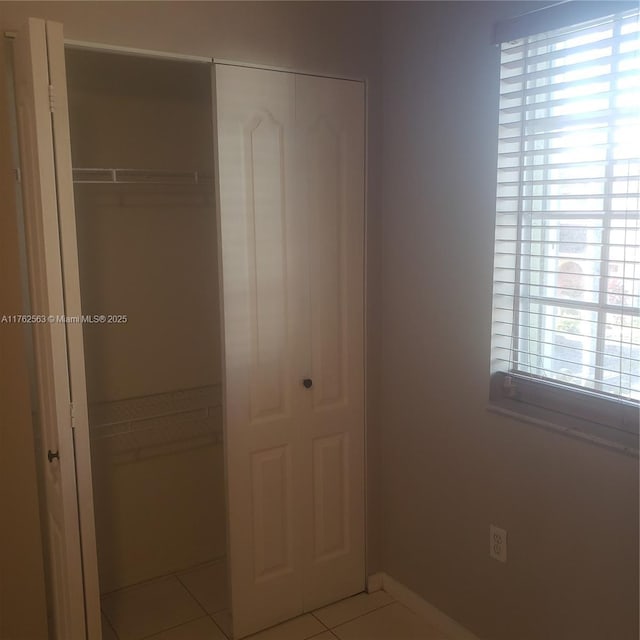 unfurnished bedroom featuring a closet, tile patterned floors, and baseboards