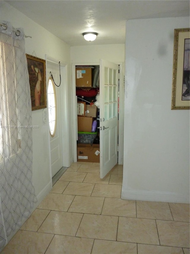 hallway with light tile patterned flooring and baseboards