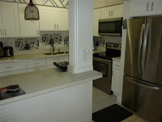 kitchen featuring a sink, backsplash, white cabinetry, stainless steel appliances, and light tile patterned floors