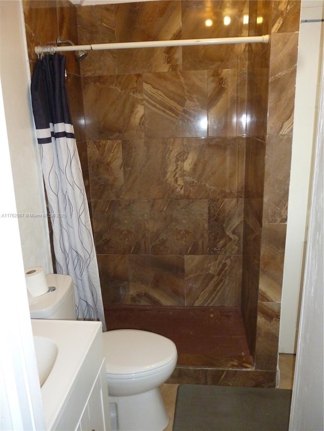 bathroom featuring toilet, vanity, and a tile shower