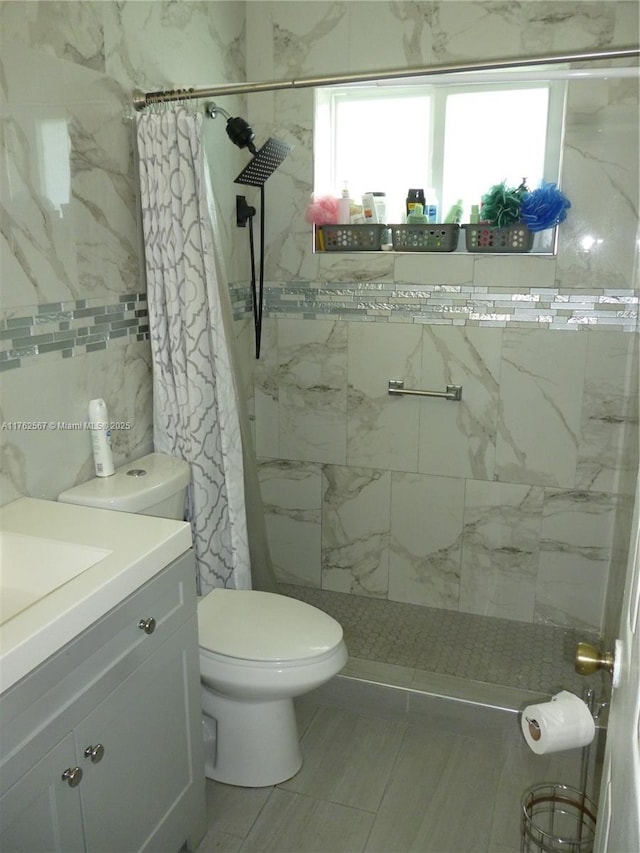 full bath featuring vanity, toilet, and tiled shower