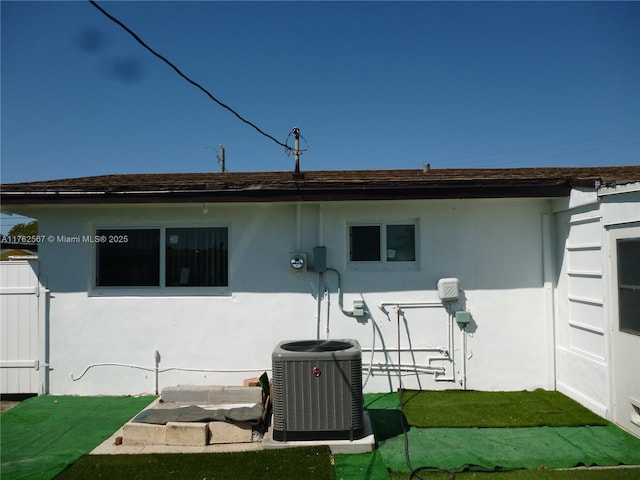 rear view of property with cooling unit and stucco siding