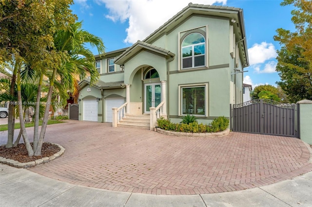 view of front of property featuring a garage, decorative driveway, stucco siding, a gate, and a tiled roof