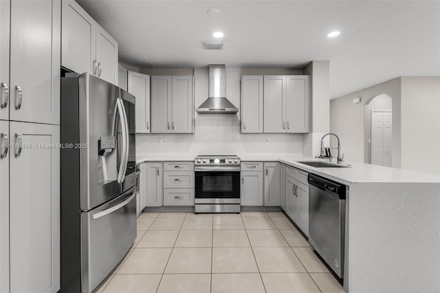 kitchen featuring light tile patterned floors, a sink, stainless steel appliances, light countertops, and wall chimney range hood