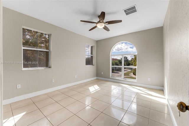 spare room with tile patterned floors, visible vents, baseboards, and ceiling fan