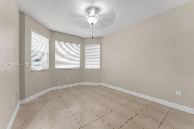 empty room with light tile patterned flooring, baseboards, and ceiling fan