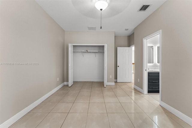 unfurnished bedroom featuring light tile patterned floors, visible vents, a closet, and baseboards