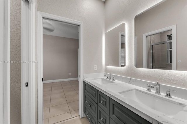 bathroom with tile patterned floors, double vanity, baseboards, and a sink