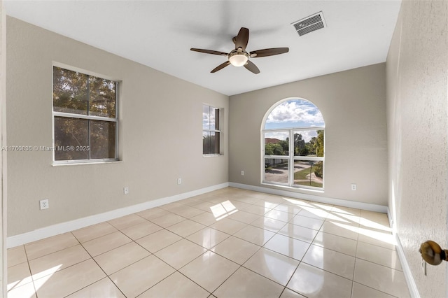 tiled spare room with ceiling fan, visible vents, and baseboards