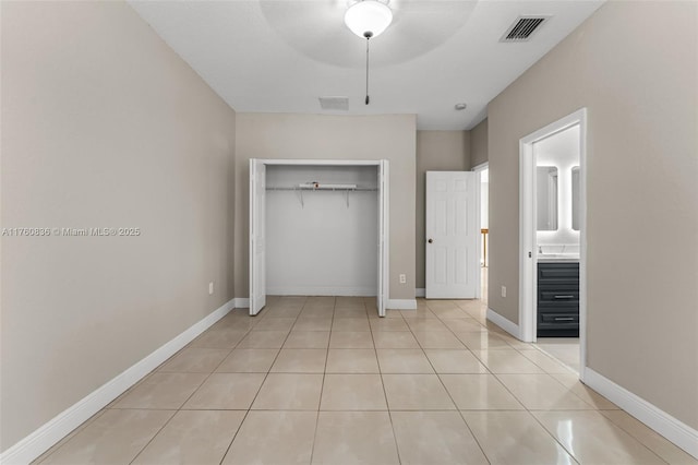 unfurnished bedroom featuring ensuite bath, light tile patterned flooring, visible vents, and a closet