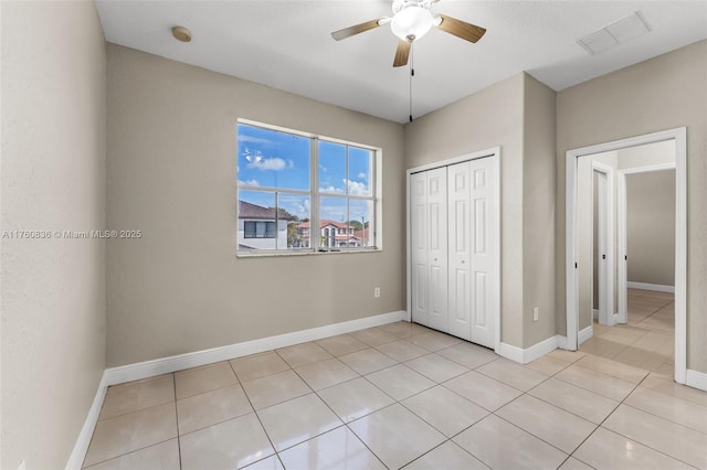 unfurnished bedroom featuring light tile patterned flooring, ceiling fan, baseboards, visible vents, and a closet