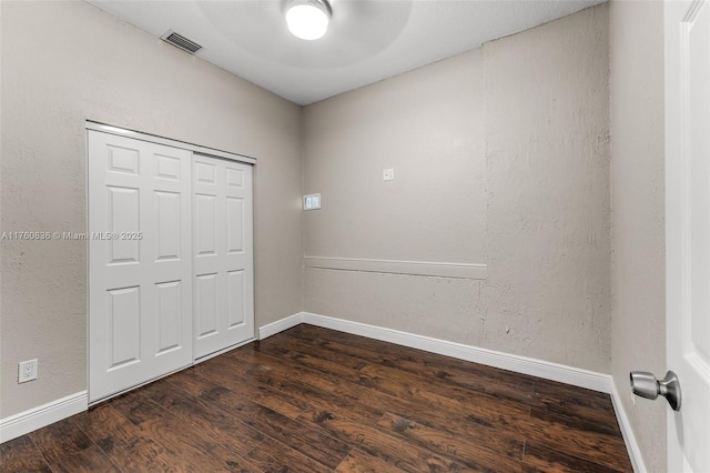 unfurnished bedroom featuring a closet, baseboards, visible vents, and dark wood-style flooring