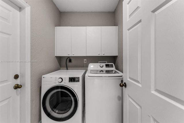 laundry room featuring separate washer and dryer, a textured wall, and cabinet space