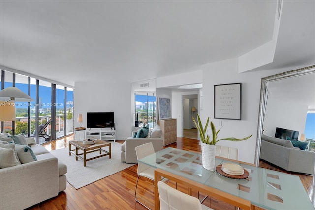 living area with a wall of windows, visible vents, and wood finished floors