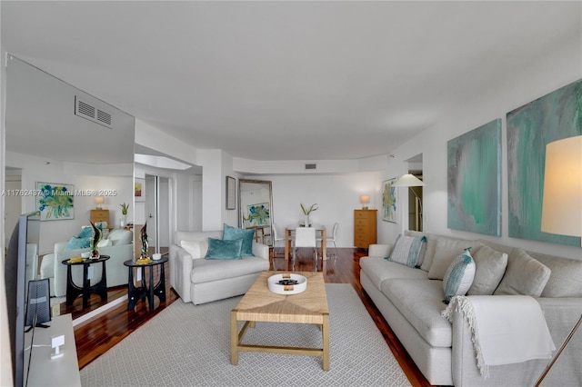 living area featuring visible vents and wood finished floors