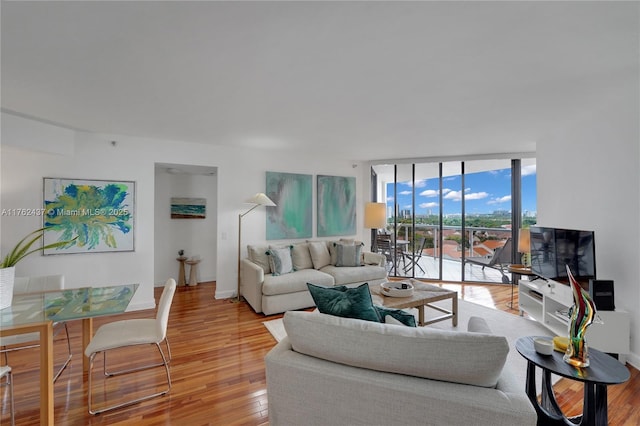 living room featuring floor to ceiling windows, light wood-style flooring, and baseboards