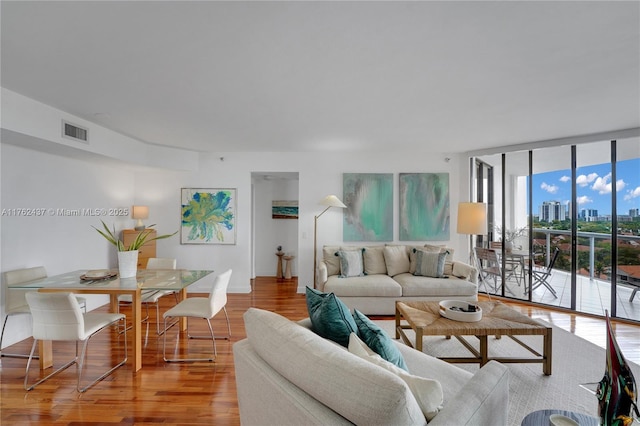 living area with visible vents, expansive windows, a city view, and wood finished floors