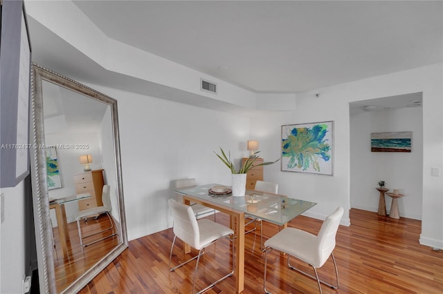 dining area featuring wood finished floors, visible vents, and baseboards