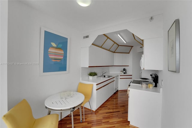 kitchen featuring light wood-style flooring, dishwasher, white cabinets, and light countertops