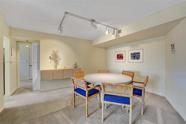 carpeted dining space featuring visible vents and a textured ceiling