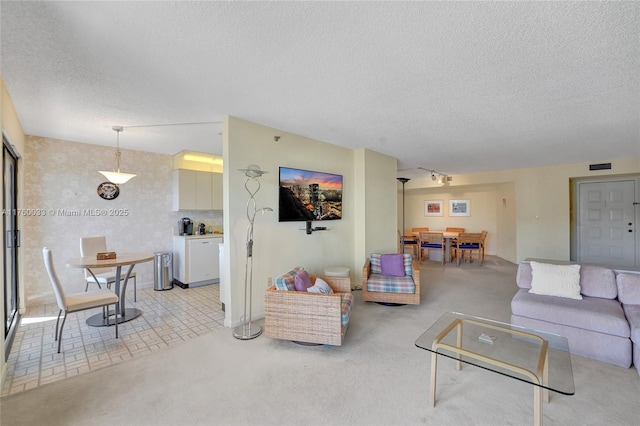 living area featuring visible vents, light colored carpet, and a textured ceiling