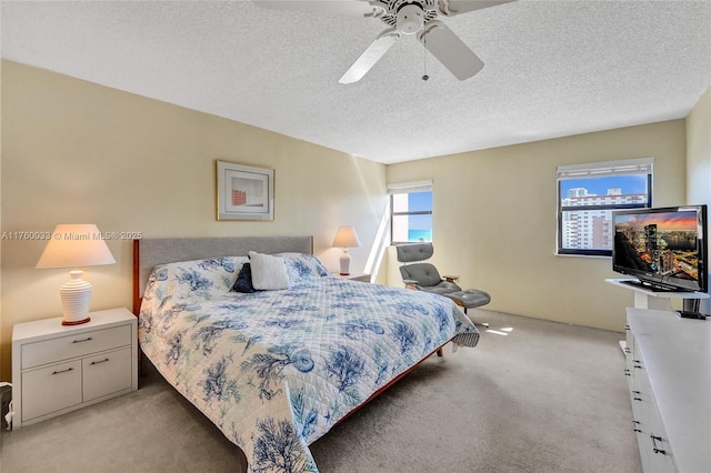 bedroom featuring light colored carpet, ceiling fan, and a textured ceiling