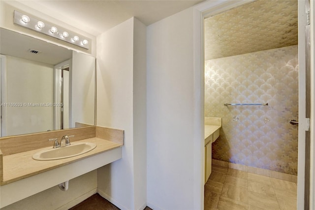 bathroom featuring wallpapered walls, vanity, baseboards, and visible vents