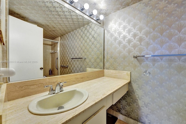 bathroom with an enclosed shower, vanity, and wallpapered walls