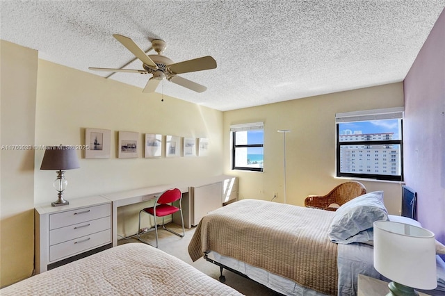 carpeted bedroom featuring a ceiling fan and a textured ceiling