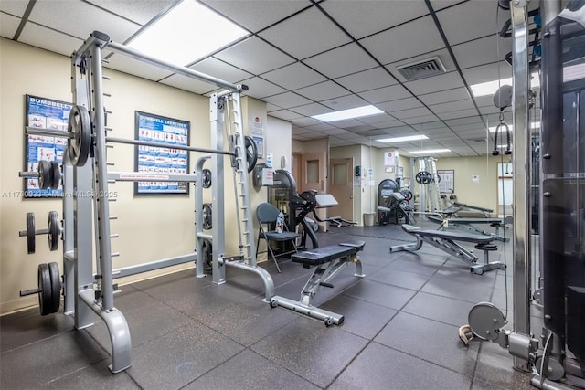 gym with a drop ceiling, visible vents, and baseboards